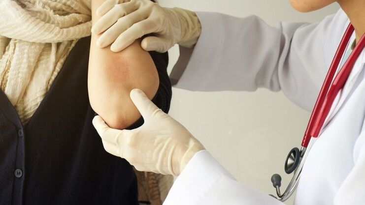 The doctor examines the elbow for psoriasis
